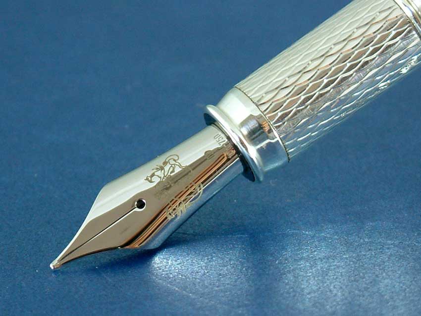 Close-up of a fountain pen nib with an engraved lion, on a silver barrel with a diamond pattern