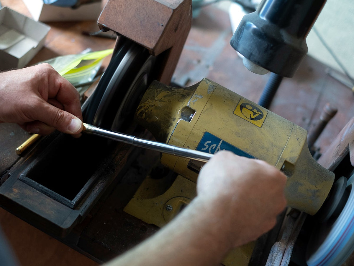 Hands polishing a pen part at the wheel in the Grifos workshop