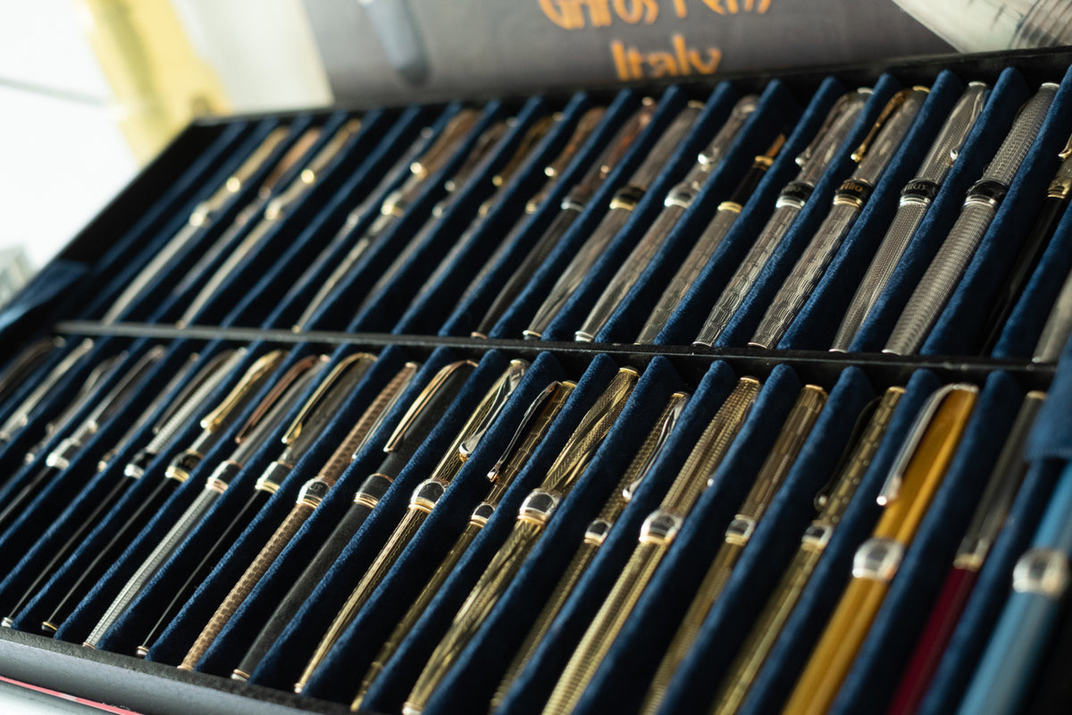 Tray with dozens of Grifos pens in silver and gold, lined up on blue velvet