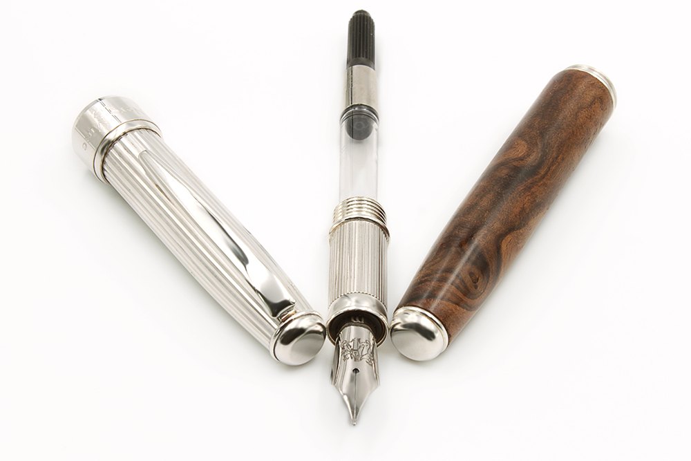Pluma estilográfica con el convertidor visible, entre un capuchón de plata a rayas y un cuerpo de madera